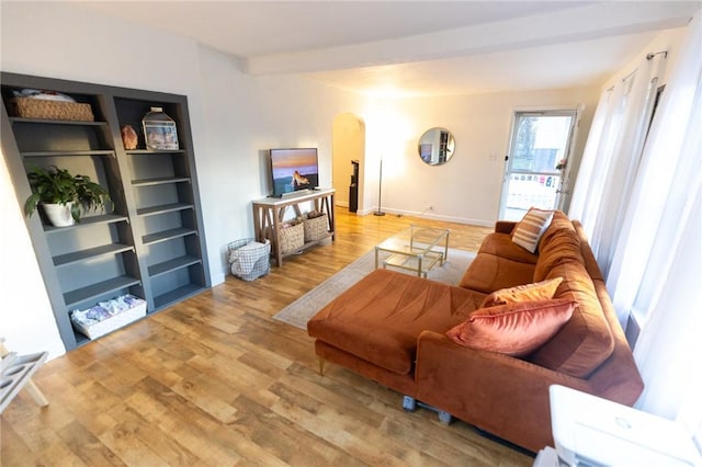 living room featuring light wood-style floors, arched walkways, and baseboards