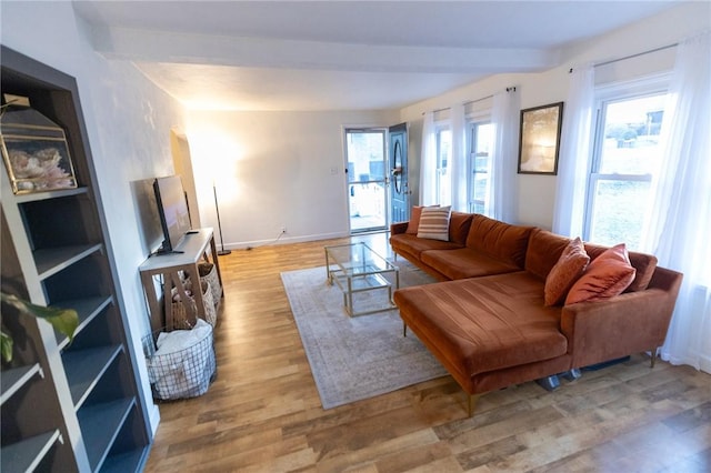 living room with beam ceiling, light wood-style flooring, and baseboards