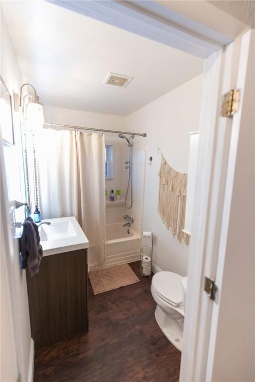 bathroom featuring visible vents, toilet, wood finished floors, shower / bath combo with shower curtain, and vanity