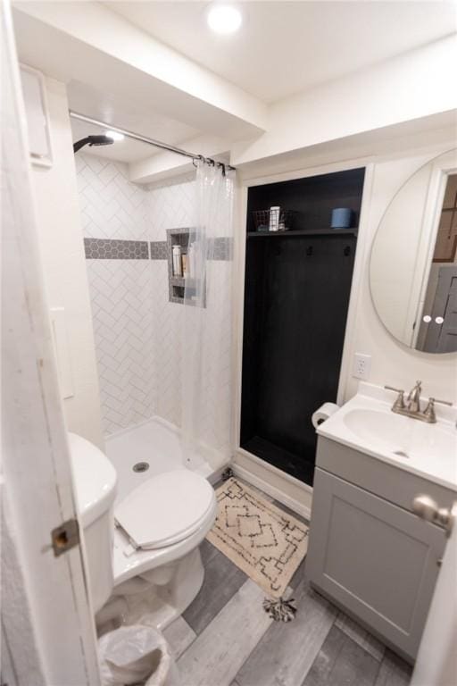 full bathroom featuring a stall shower, vanity, and toilet