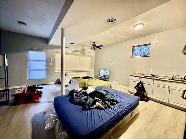 bedroom with baseboards, visible vents, and wood finished floors