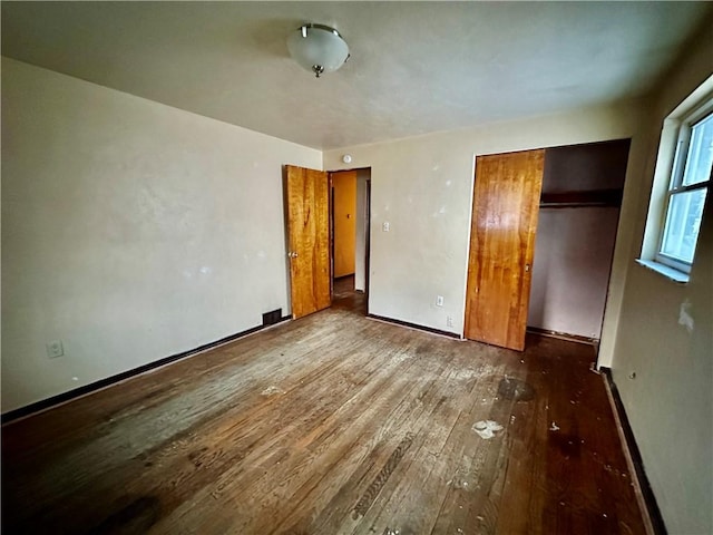 unfurnished bedroom featuring a closet, baseboards, and hardwood / wood-style flooring