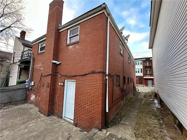 view of property exterior with brick siding and a chimney