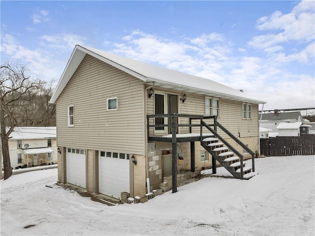 exterior space featuring an attached garage, fence, and stairway