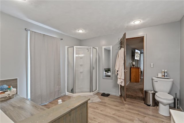 full bath with wood finished floors, a shower stall, toilet, and baseboards