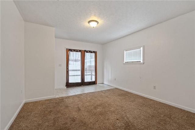 empty room with a healthy amount of sunlight, light carpet, a textured ceiling, and baseboards