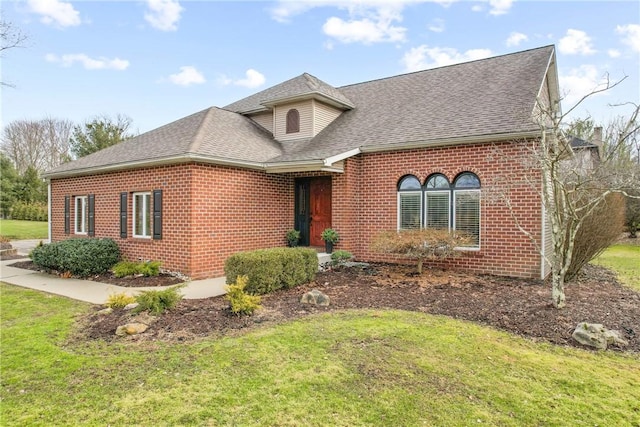 view of front of property with brick siding, roof with shingles, and a front yard