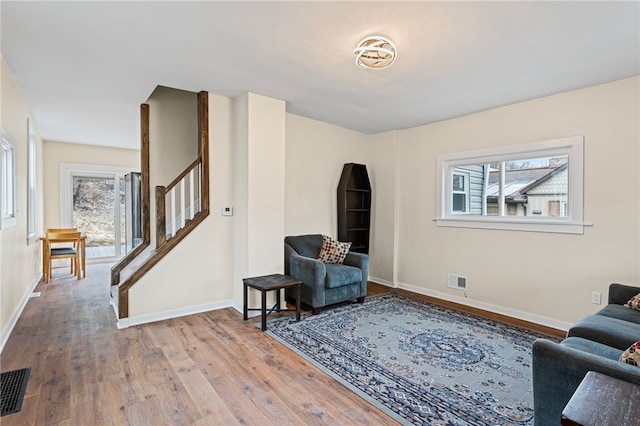 living area featuring visible vents, stairway, baseboards, and hardwood / wood-style flooring