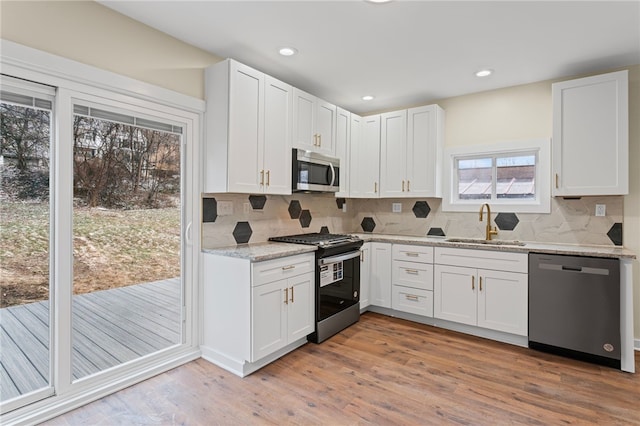 kitchen featuring stainless steel appliances, light wood finished floors, a sink, and white cabinets