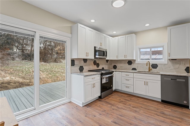 kitchen featuring appliances with stainless steel finishes, white cabinets, a sink, and wood finished floors