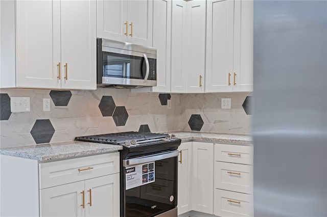 kitchen featuring appliances with stainless steel finishes, tasteful backsplash, white cabinetry, and light stone countertops