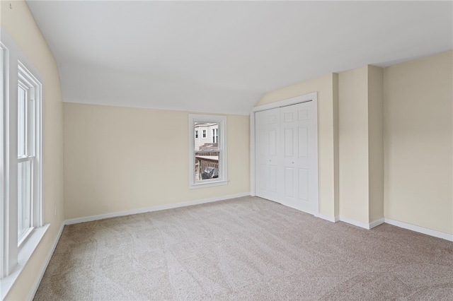 unfurnished bedroom featuring lofted ceiling, carpet floors, a closet, and baseboards