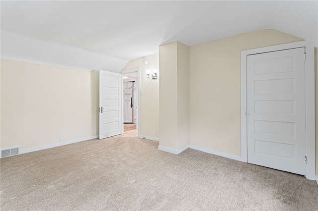 empty room with lofted ceiling, baseboards, visible vents, and carpet flooring