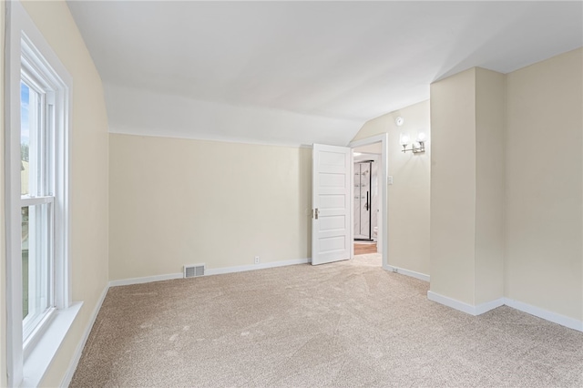 carpeted empty room with lofted ceiling, visible vents, and baseboards