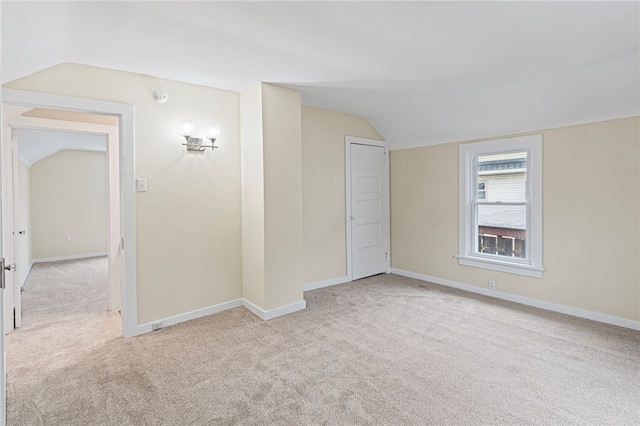 carpeted empty room with lofted ceiling and baseboards