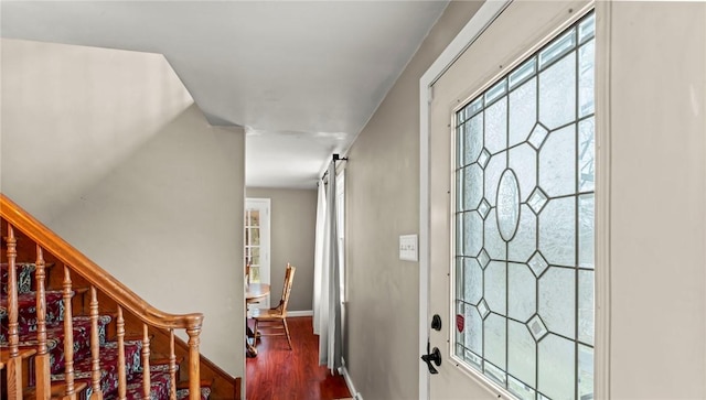 foyer with dark wood-type flooring, stairway, baseboards, and a barn door