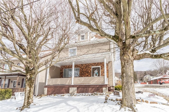 american foursquare style home featuring stone siding and a porch