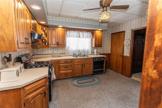 kitchen featuring wainscoting, a sink, under cabinet range hood, black appliances, and wallpapered walls