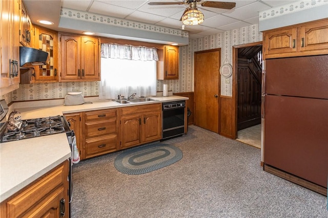 kitchen featuring wainscoting, stainless steel range with gas stovetop, a sink, dishwasher, and wallpapered walls