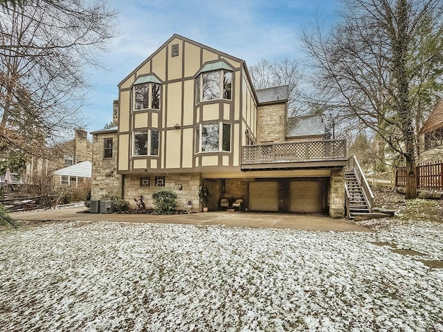 rear view of property featuring an attached garage, stone siding, concrete driveway, and stucco siding