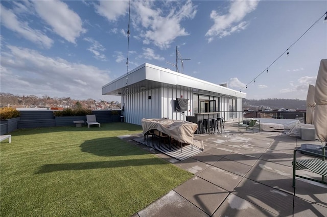 rear view of property with a patio area, a lawn, outdoor dry bar, and fence