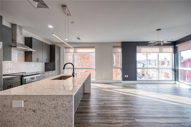 kitchen with visible vents, decorative backsplash, wall chimney exhaust hood, stainless steel electric range, and a sink