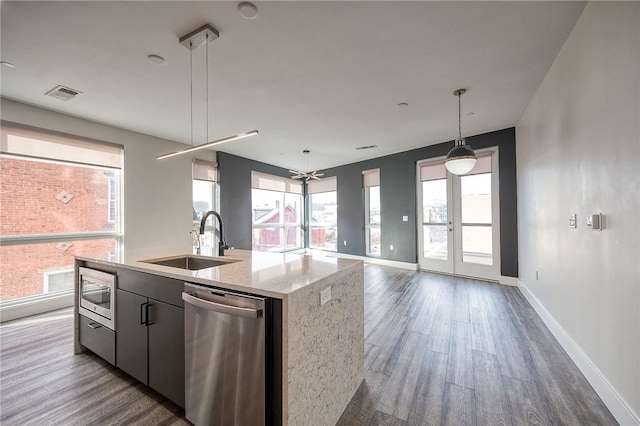 kitchen with visible vents, an island with sink, dark wood-style flooring, stainless steel appliances, and a sink