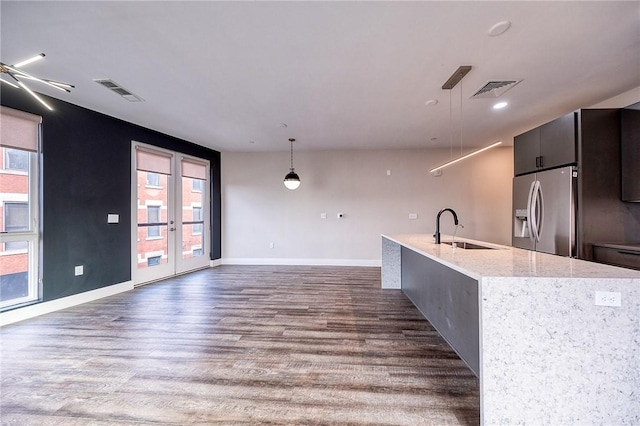 kitchen featuring pendant lighting, stainless steel refrigerator with ice dispenser, visible vents, dark wood-type flooring, and a sink