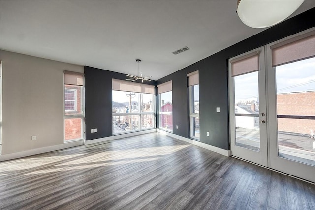 unfurnished dining area with baseboards, visible vents, wood finished floors, and french doors