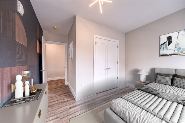 bedroom with a closet, light wood-style flooring, and baseboards