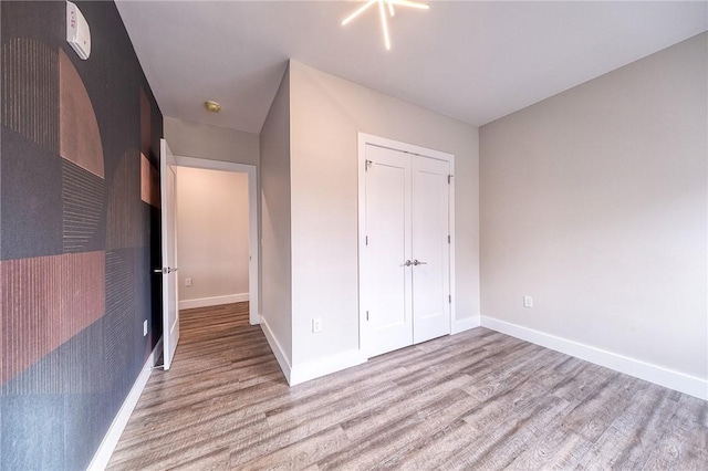 unfurnished bedroom with a closet, baseboards, and wood finished floors