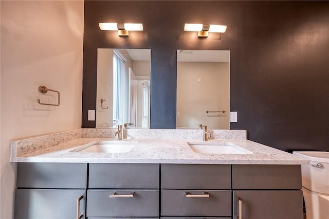 full bath featuring double vanity, a sink, and toilet