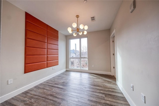 spare room with a notable chandelier, baseboards, visible vents, and dark wood-style flooring