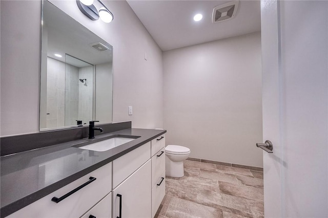 bathroom featuring toilet, visible vents, a tile shower, and vanity