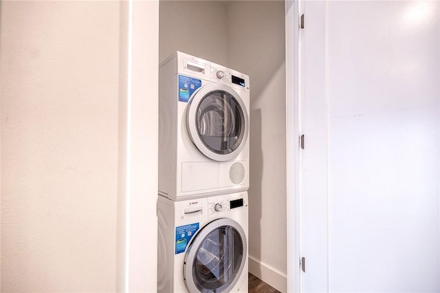 clothes washing area with stacked washer and dryer, laundry area, and baseboards