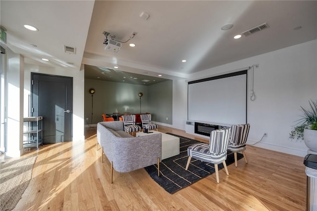 cinema room with light wood-style floors, recessed lighting, and visible vents