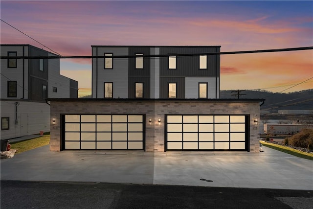 view of front of home with a garage, concrete driveway, an outdoor structure, and stone siding