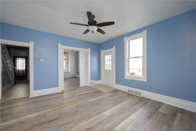 unfurnished room featuring baseboards, visible vents, ceiling fan, and wood finished floors
