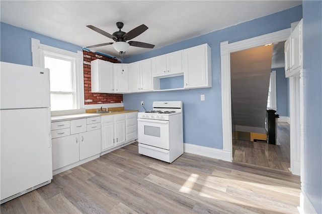 kitchen featuring white appliances, light wood-type flooring, a sink, and white cabinetry