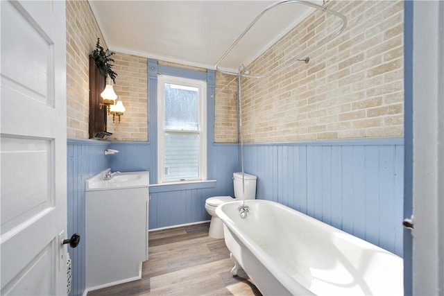 bathroom featuring a freestanding bath, toilet, wainscoting, vanity, and wood finished floors