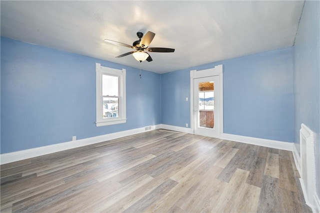 spare room featuring a ceiling fan, visible vents, baseboards, and wood finished floors