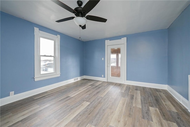 empty room featuring visible vents, ceiling fan, baseboards, and wood finished floors