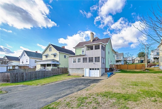 view of front facade featuring a chimney, a front yard, and fence