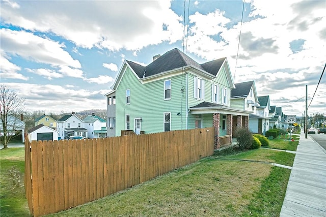 view of side of home with a residential view, fence, and a lawn