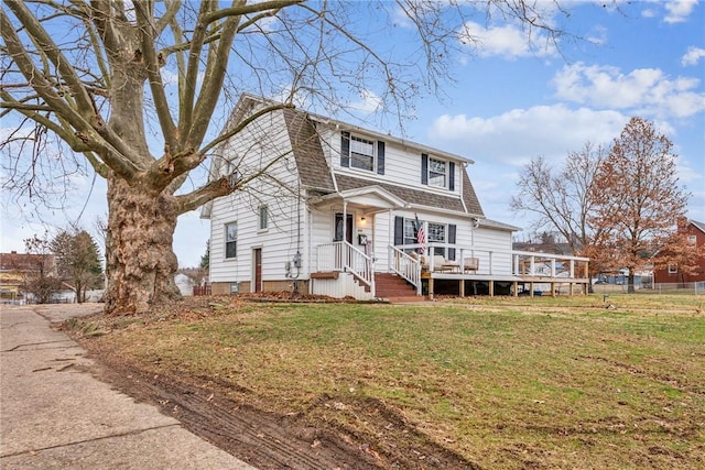 colonial inspired home with a shingled roof, a front lawn, fence, and a gambrel roof