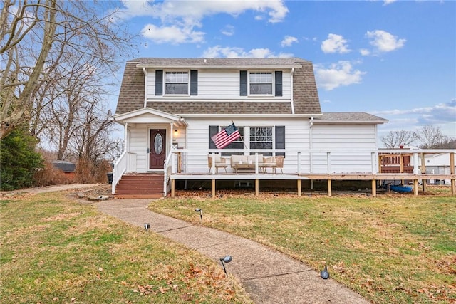 dutch colonial featuring a wooden deck, a front lawn, and roof with shingles