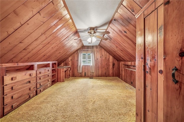 additional living space with carpet floors, lofted ceiling, wooden walls, and a ceiling fan