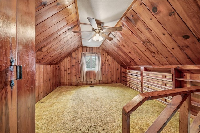 additional living space with lofted ceiling, wooden walls, a ceiling fan, and carpet flooring