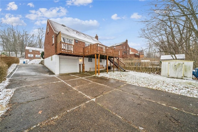 back of property with a deck, driveway, stairway, and an attached garage