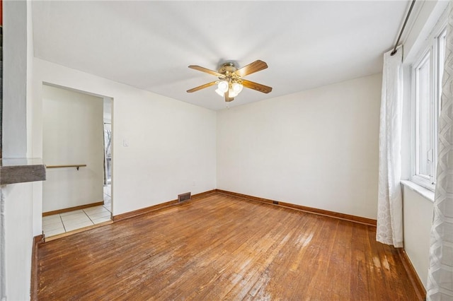 unfurnished room featuring light wood-type flooring, baseboards, visible vents, and ceiling fan